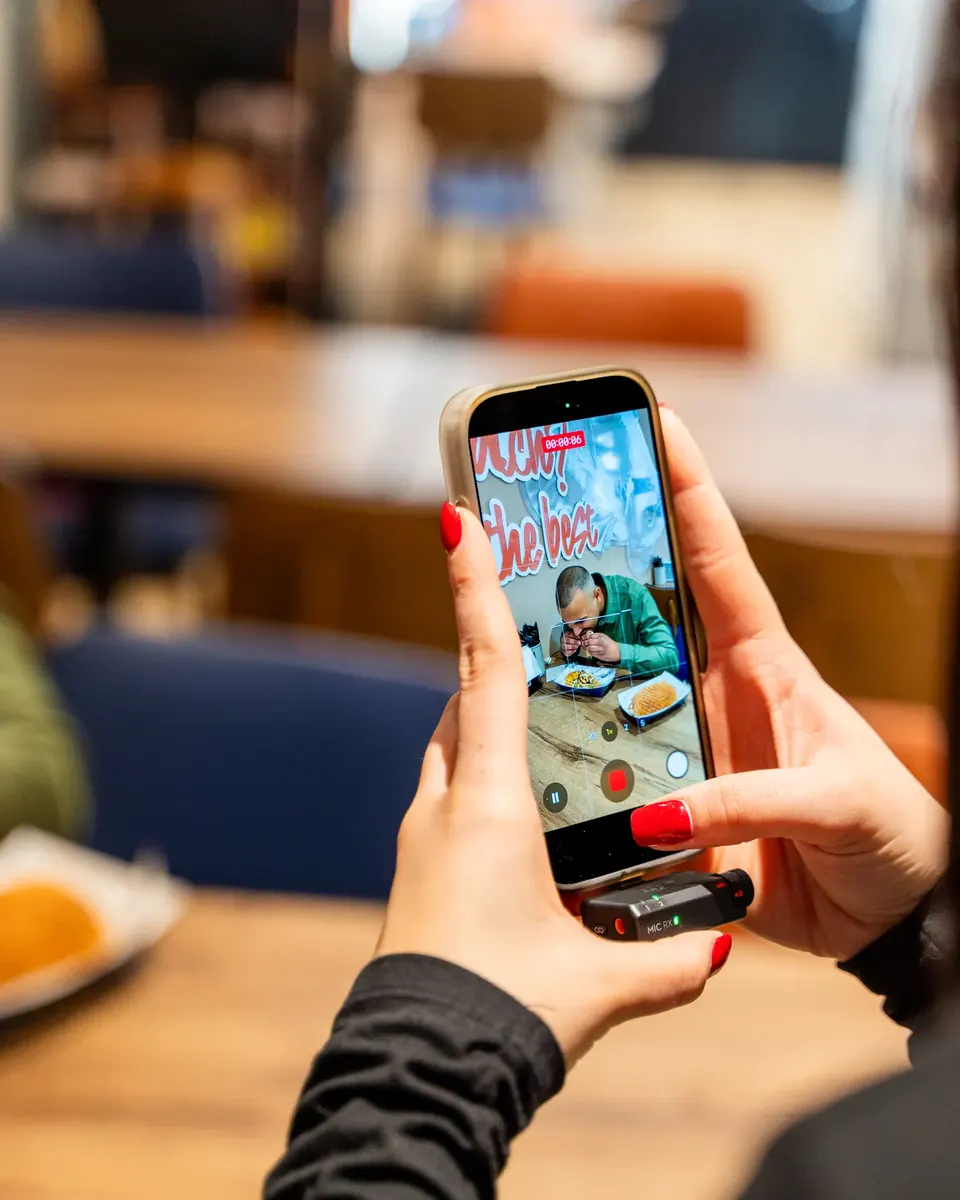 Hand hält Smartphone und filmt ein Gericht für ein Instagram-Reel im Restaurant